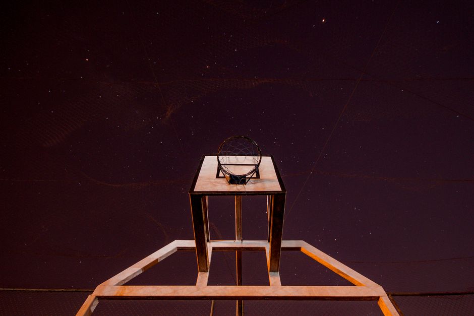 A low angle shot of a basketball hoop against a starry night sky.