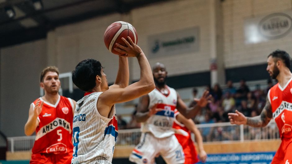 Dynamic basketball game indoors with players in mid-action, showcasing teamwork and competition.