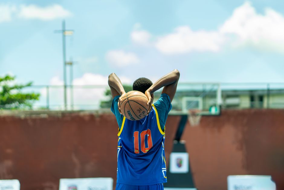 A young athlete prepares for a basketball shot on an outdoor court in Nigeria.