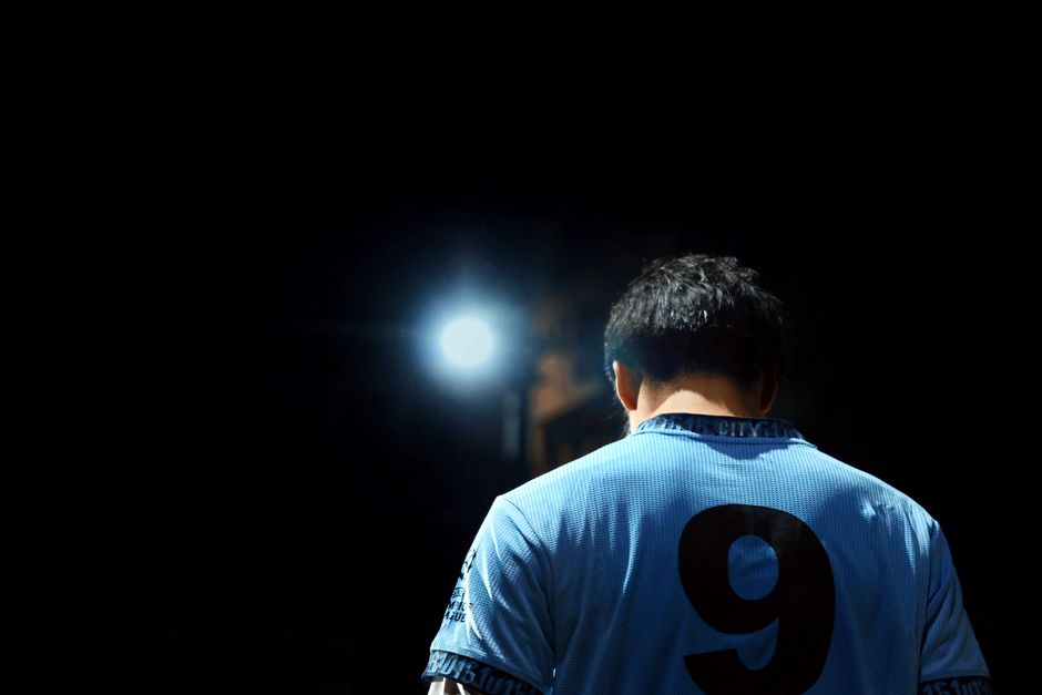 A soccer player in a blue jersey with number 9, illuminated by a spotlight at night.