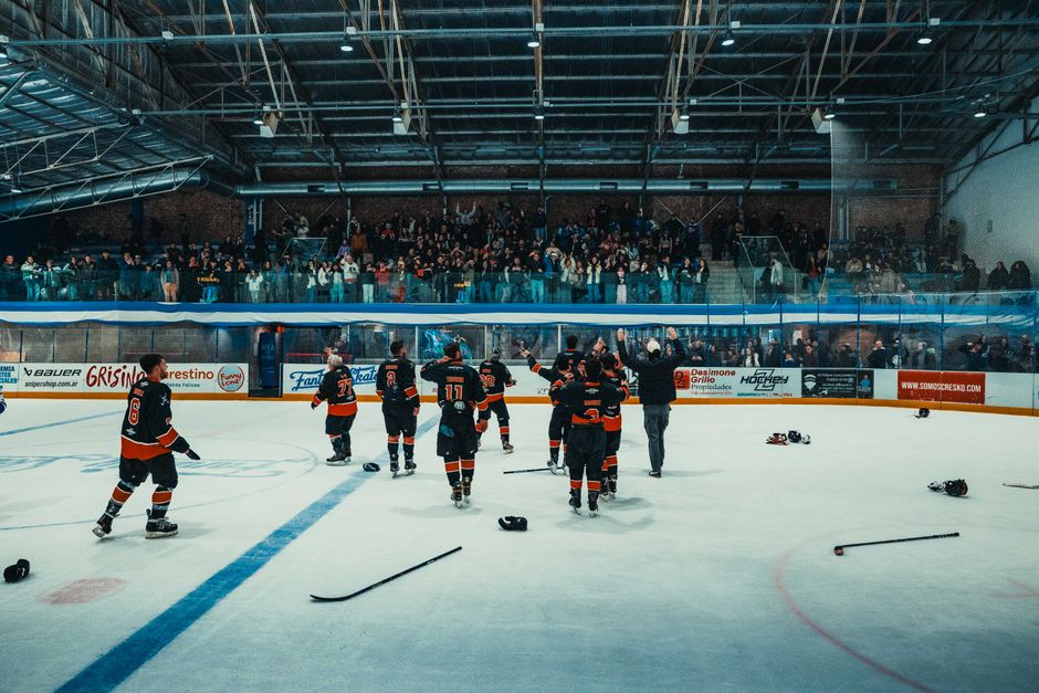 Ice hockey team celebrates victory in Buenos Aires indoor arena with cheering crowd.